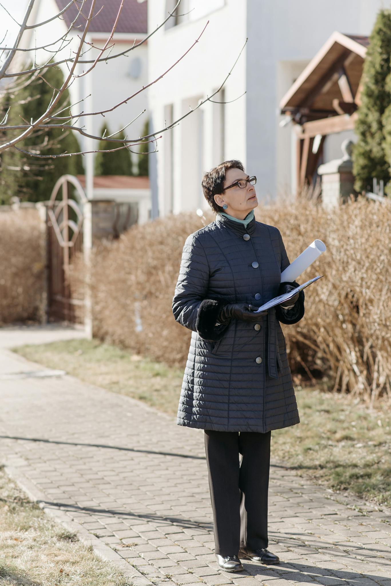 Professional real estate agent observing a property outdoors in winter.